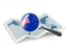 Новая Зеландия. Флаг под увеличительным стеклом над картой. Скачать иконку.